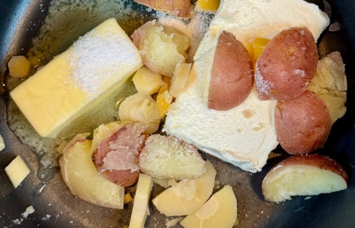 adding butter and cream cheese to potatoes