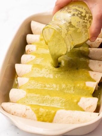 pouring green sauce on enchiladas