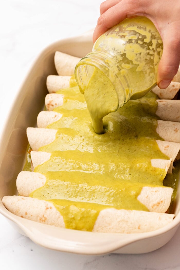 pouring green sauce on enchiladas