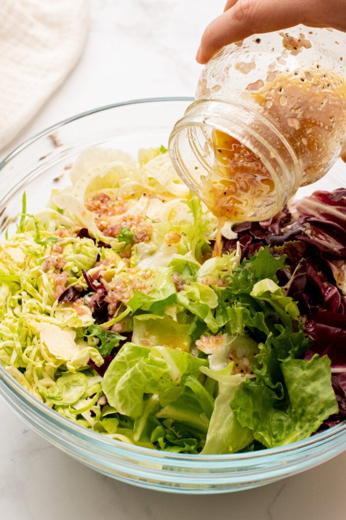 pouring dressing over fresh greens