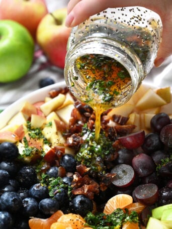 pouring dressing over winter fruit salad
