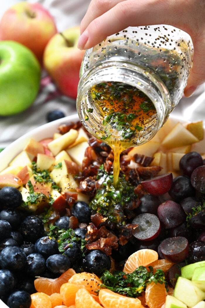 pouring dressing over winter fruit salad
