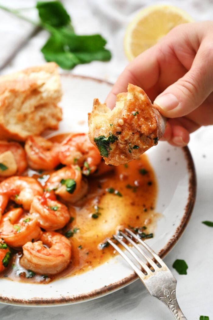 dipping crusty bread in the sauce