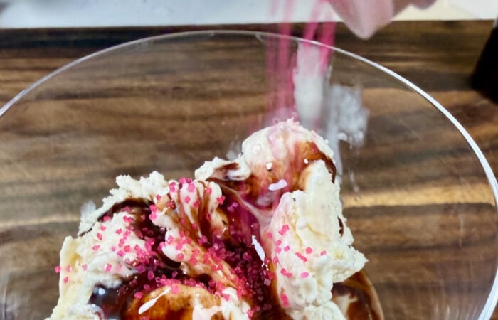 adding pink sprinkles to chocolate ice cream