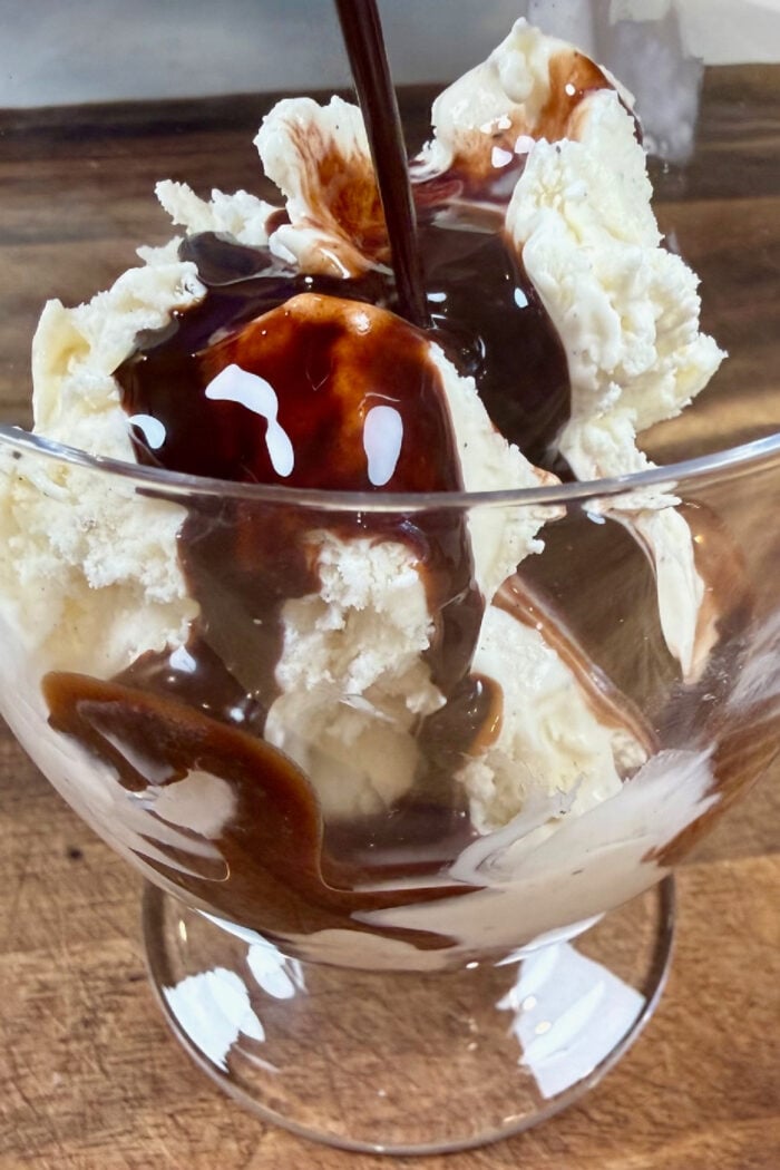 adding chocolate sauce to ice cream