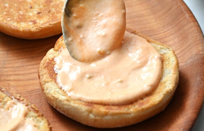 adding special sauce to a bun