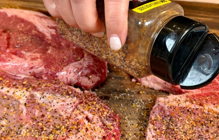 sprinkling Monterey Steak Seasoning meat
