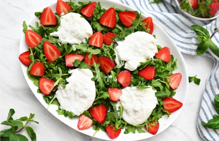 adding burrata and strawberries to salads