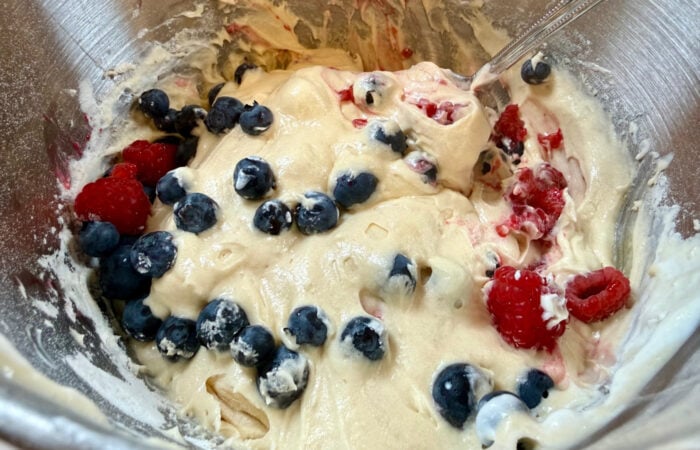 adding blueberries and raspberries to cake batter