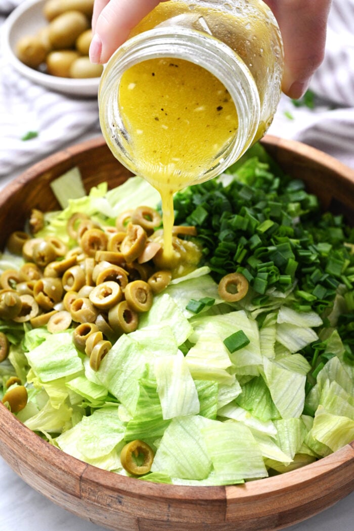 pouring dressing on iceberg salad