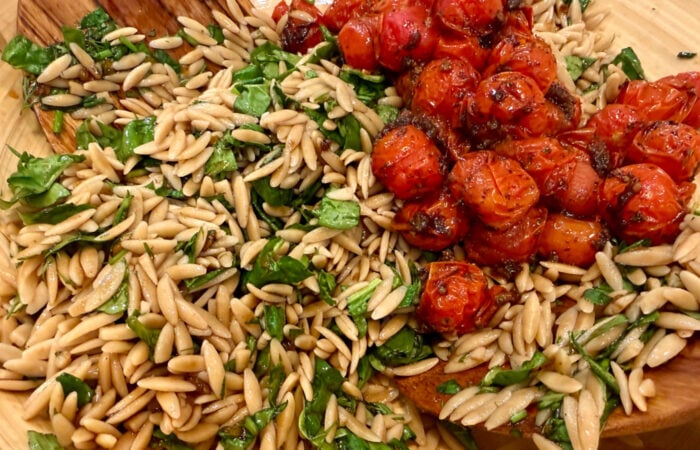 adding roasted tomatoes to orzo