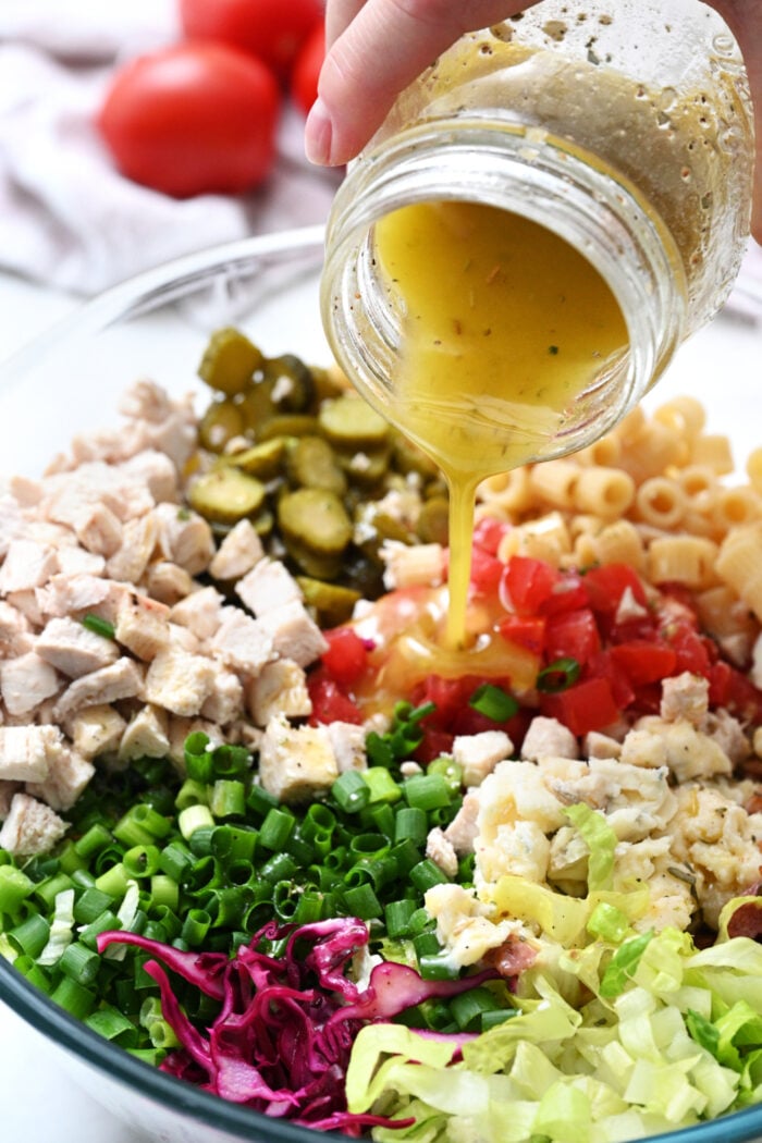 pouring dressing on a Ditalini salad