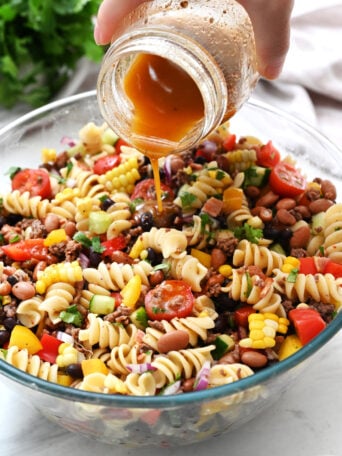 pouring dressing on pasta