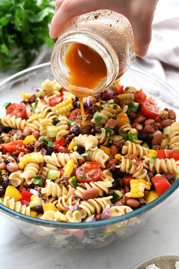 pouring dressing on pasta