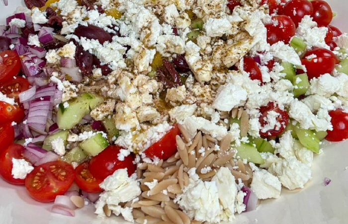 adding dressing to orzo salads