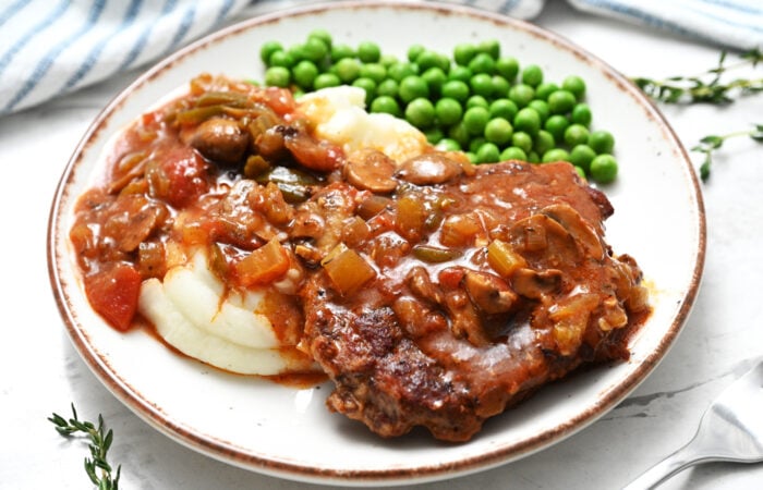 a serving steak with peas and potatoes